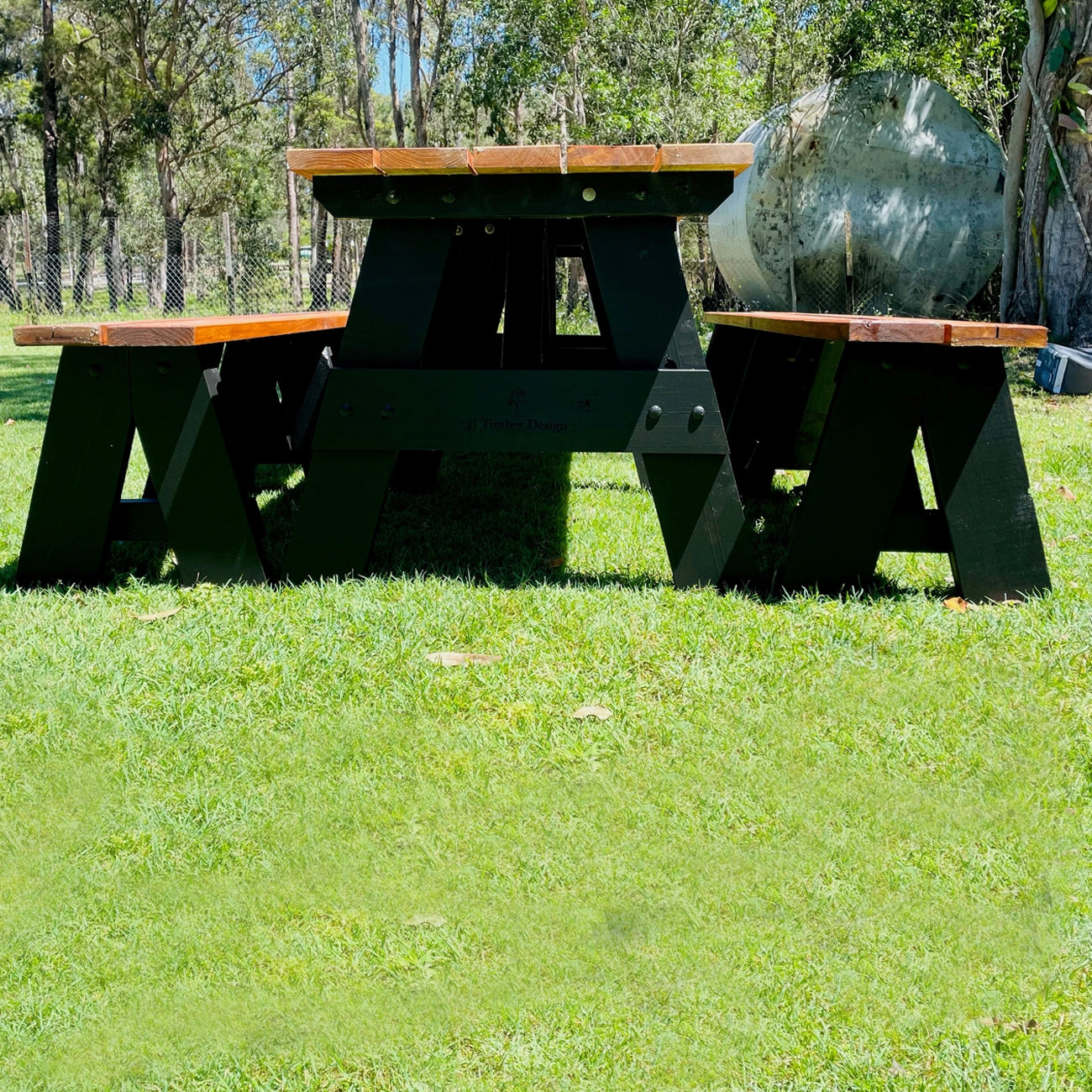 Dark timber JJ Timber Design picnic table with black supports in a sunny park.