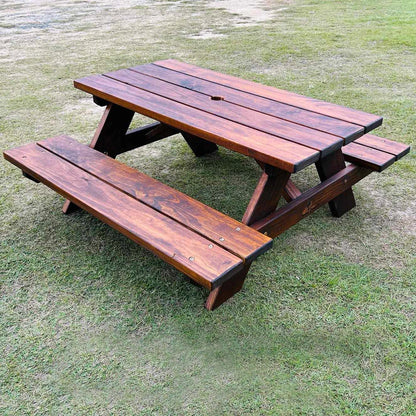 A dark brown wooden child sized picnic table with attached benches, placed on a grassy lawn. Handmade Picnic bench by JJ Timber Designs