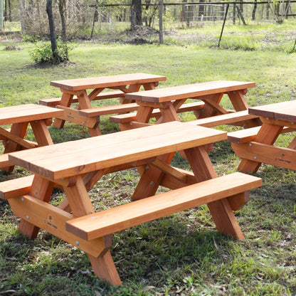 Several JJ Timber kids picnic tables arranged outdoors on grass.