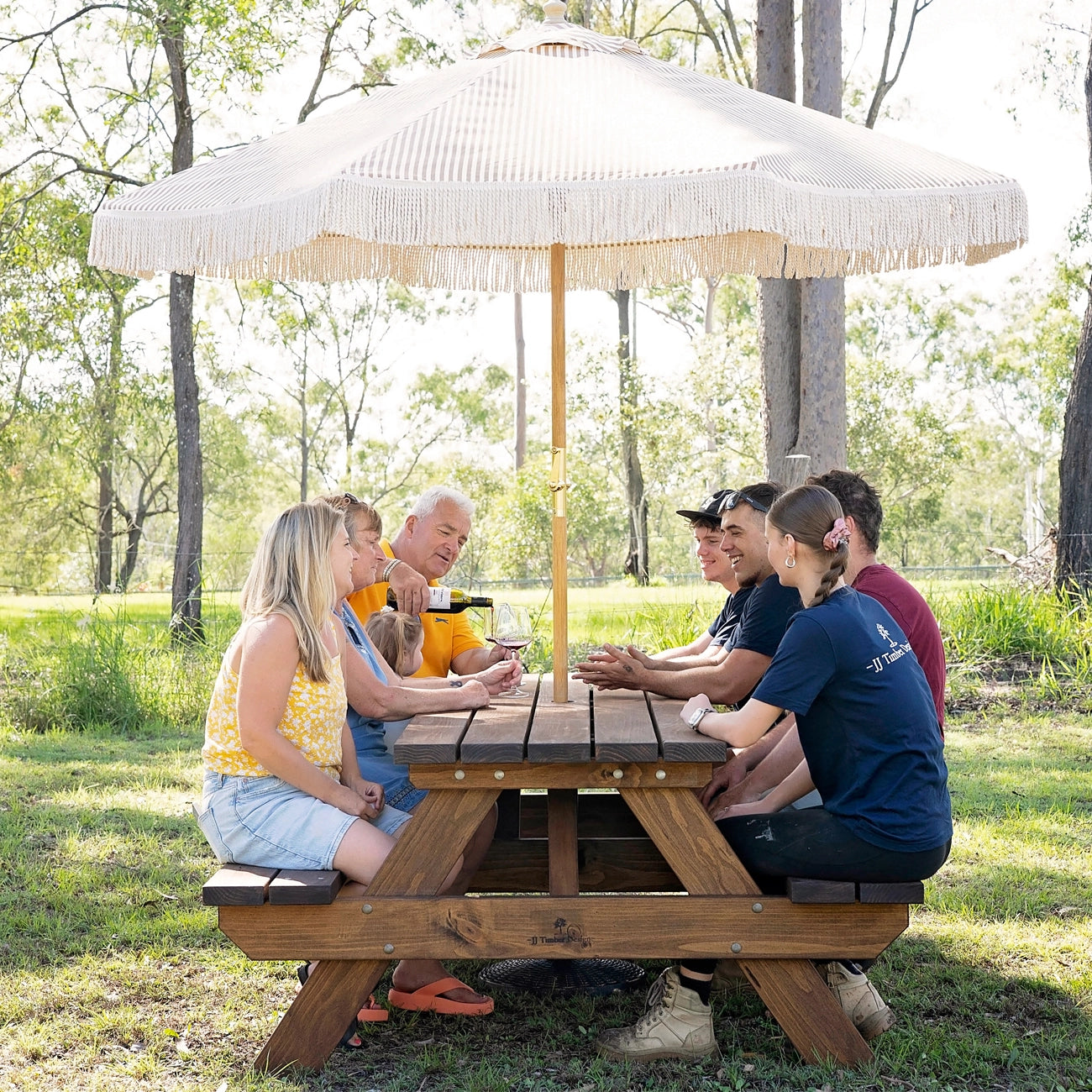 Group seated comfortably around JJ Timber 2.4m heavy duty picnic table outdoors.