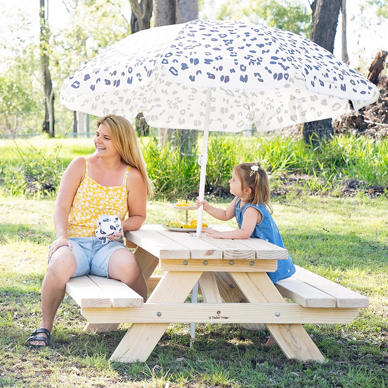 Kids sitting around JJ Timber timber kids picnic table in outdoor play area.