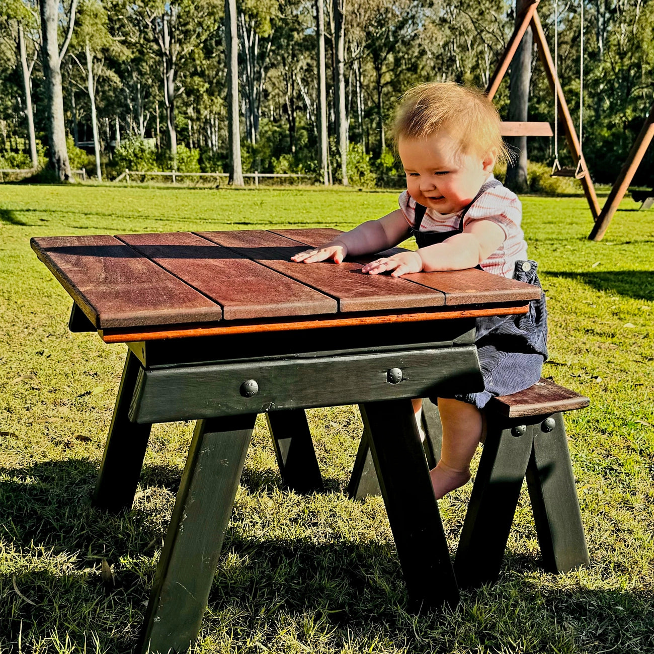 A child plays at a sensory table featuring a removable wooden lid, allowing a switch between flat tabletop and sensory-tub play. Ideal for childcare centres, backyards, and early learning play.