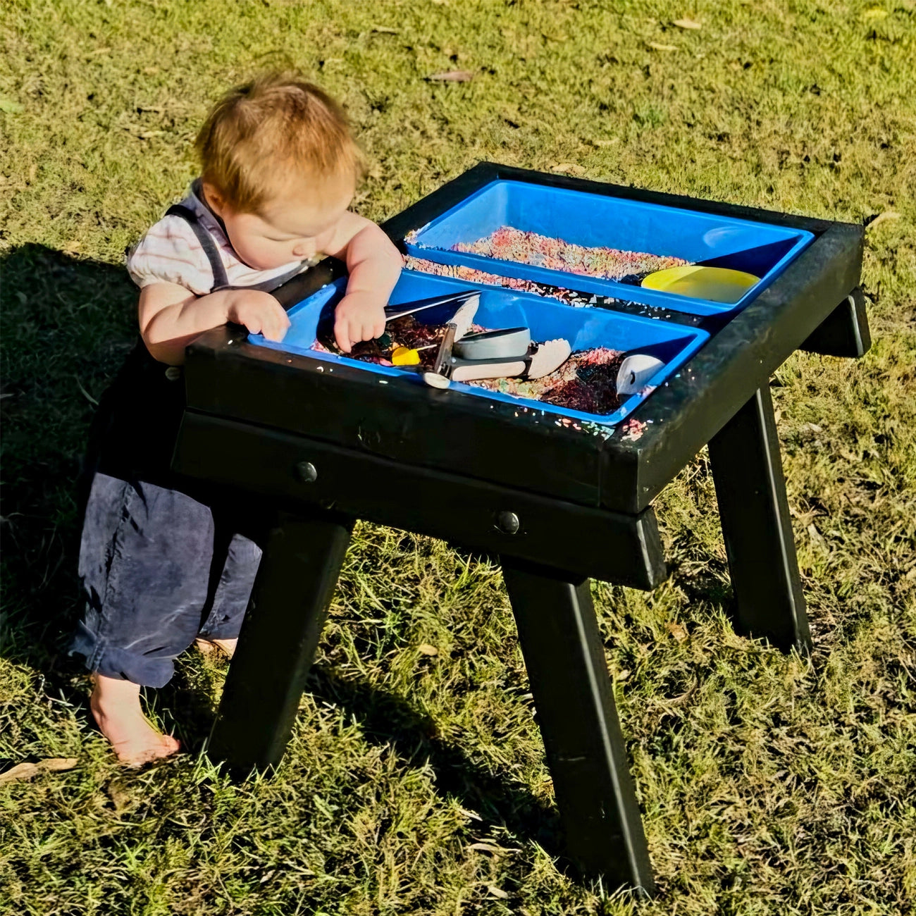 An infant playing with a handmade wooden sensory table By JJ Design