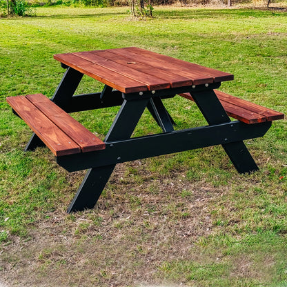 A wooden picnic table with attached benches, featuring a reddish-brown stained wood top and black wooden frame, set on a grassy lawn. Handmade by JJ Timber Design