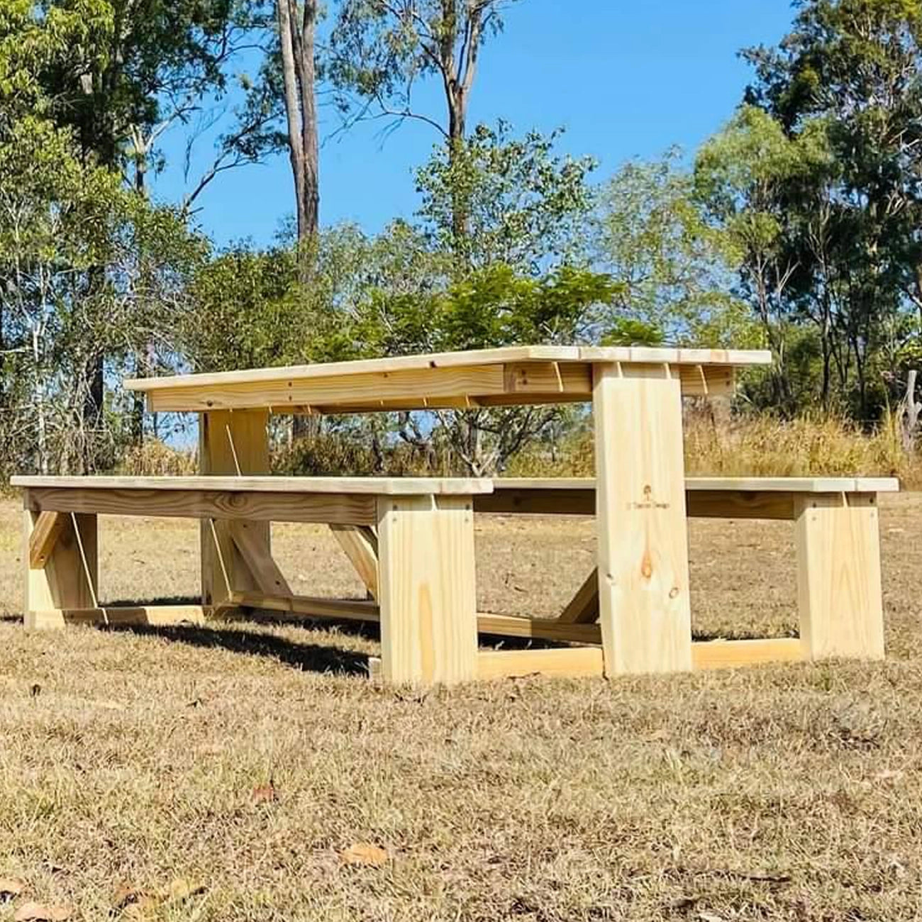 Freshly built natural JJ Timber Design picnic table placed on dry lawn.