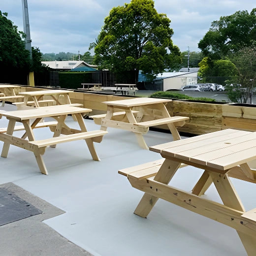 JJ Timber Design timber picnic tables arranged on a patio near water views.