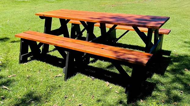Glossy stained two-tone JJ Timber Design picnic table on grass.