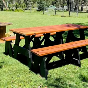 Stained JJ Timber Design picnic table with black legs placed on a grassy field.