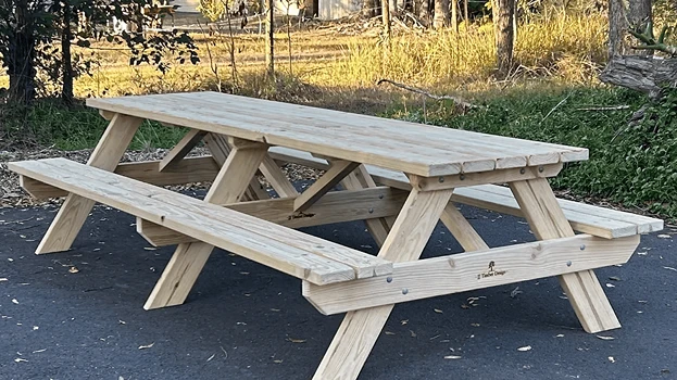Grey-washed JJ Timber Design picnic table outdoors in natural park.