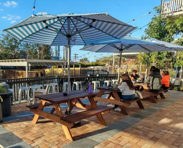 JJ Timber Design timber tables arranged under a large metal shade umbrella.