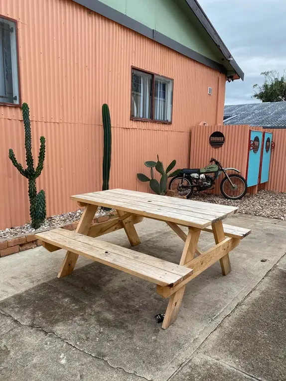JJ Timber Design natural picnic table placed outside a colourful building.