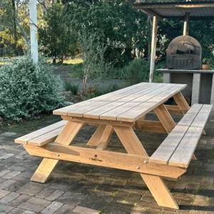 Natural light timber JJ Timber Design picnic table in a leafy garden space.