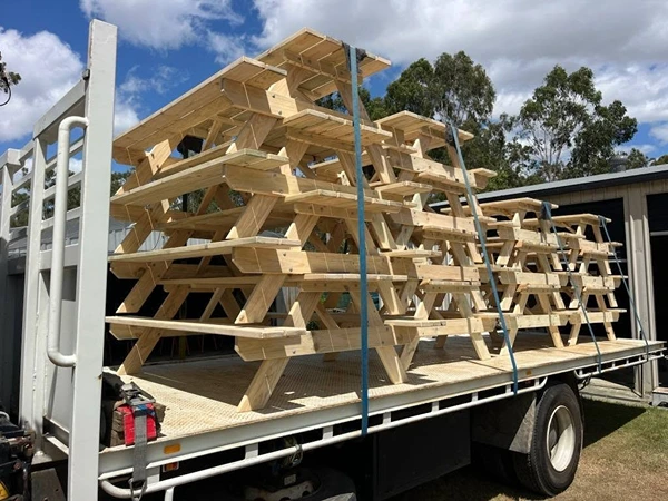 Dozens of JJ Timber Design picnic tables stacked for transport on a truck.