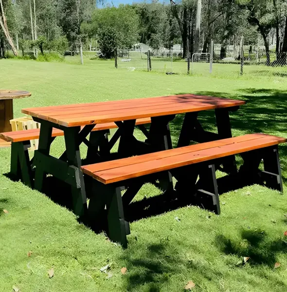 Two stained JJ Timber Design picnic tables on a grass field.
