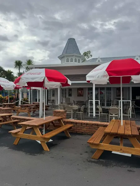 A custom timber picnic table positioned beneath outdoor umbrellas in a commercial setting