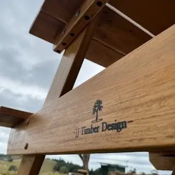 Close-up of JJ Timber Design branding on a hardwood picnic table showing timber grain and finish