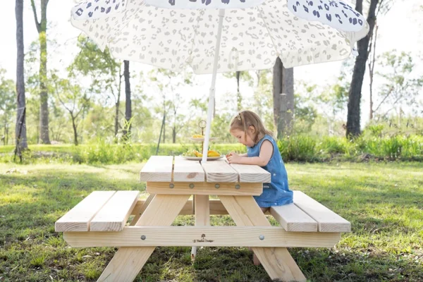 JJ Timber kids picnic table with umbrella in outdoor garden play area.